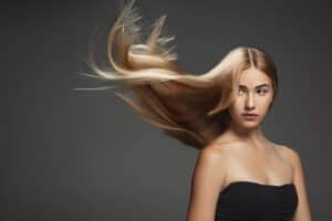 beautiful model with long smooth flying blonde hair isolated dark grey studio background young caucasian model with well kept skin hair blowing air min